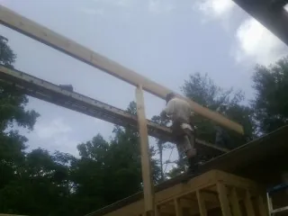 Carpenter setting a ridge beam over a new addition frame — Ice Dam Removal by Roofing Brothers in Urbanna