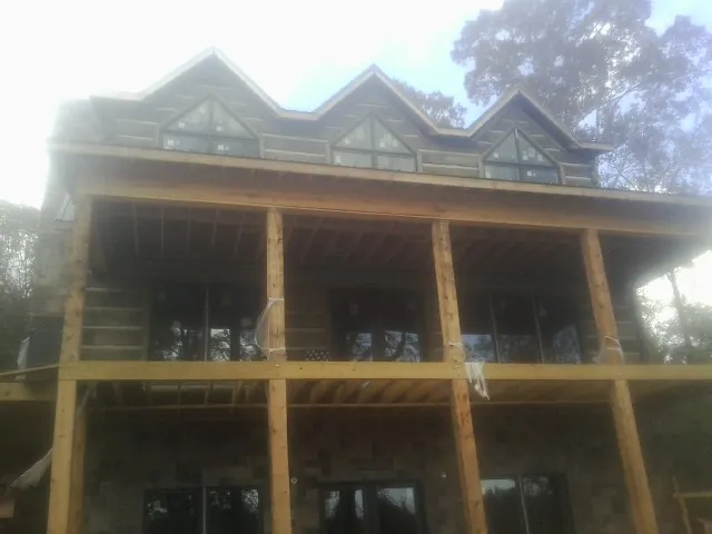 Dormers and porch framing on a large log home under construction — Roof Coating work by our crew in Urbanna