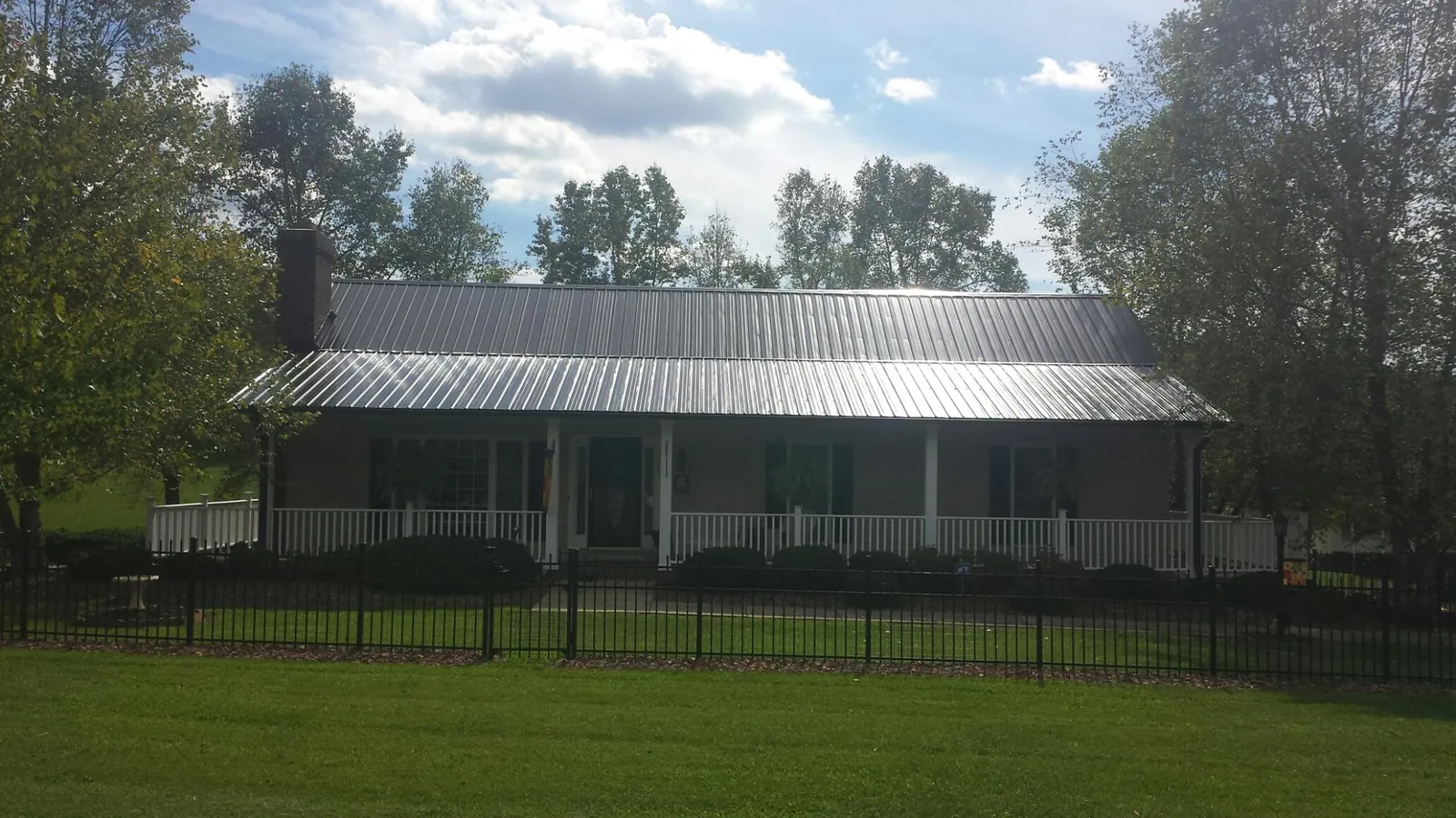 Gray metal roof on a brick ranch with a full width front porch — Gutter Guard Installation work by our crew in Urbanna