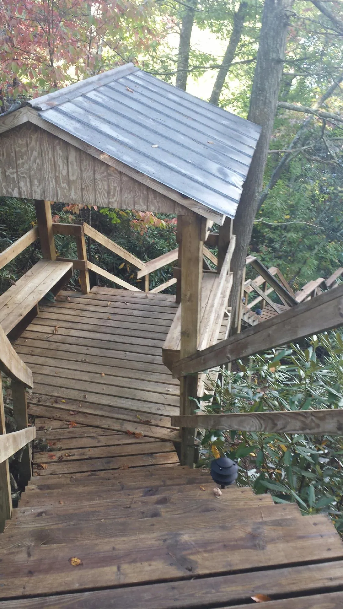Metal roofed shelter over wooden steps on a wooded walkway — Skylight Repair & Installation work by our crew in Urbanna