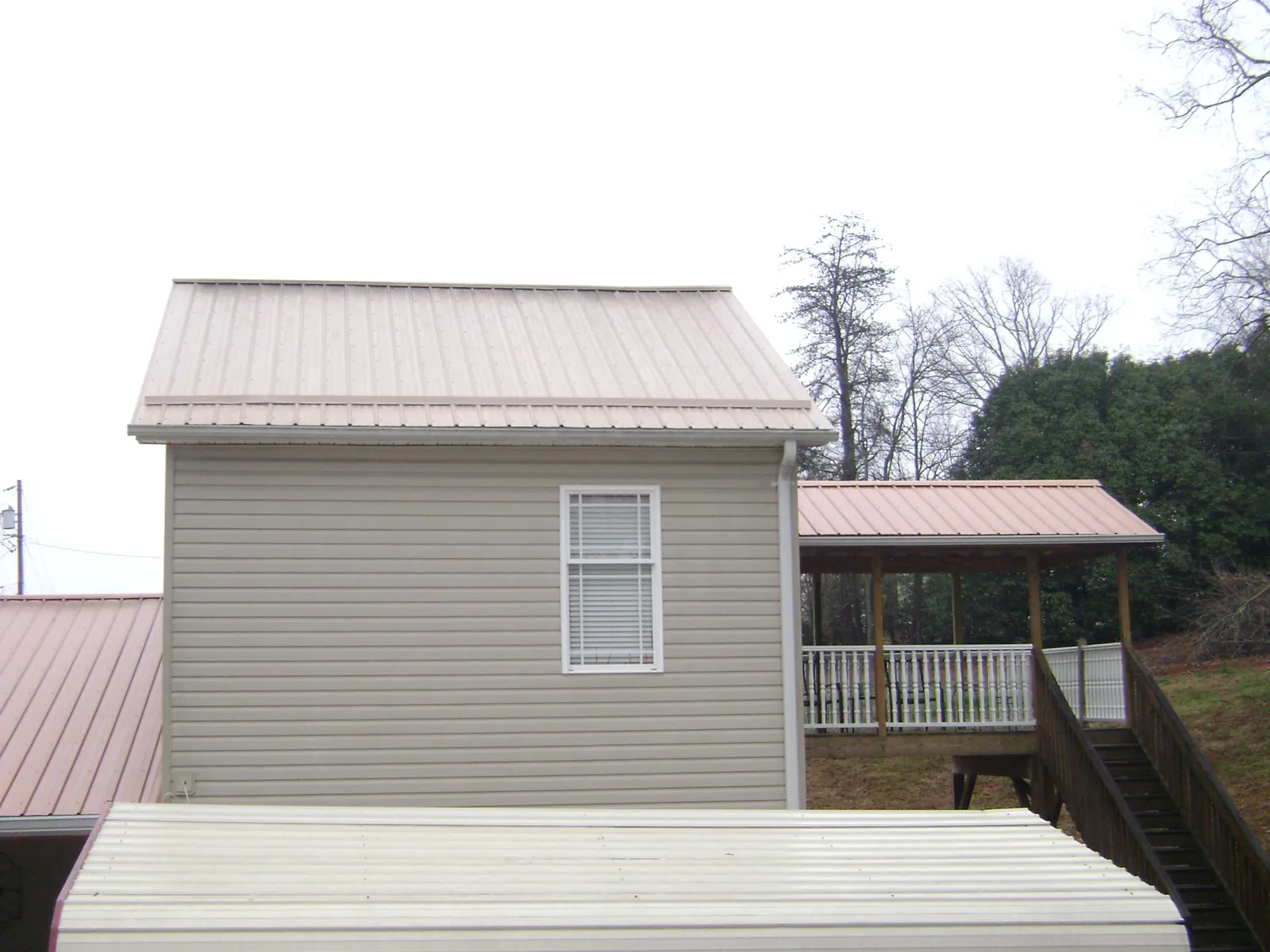 Tan metal roofs on a two story addition and attached porch, from a Roof Replacement job in Urbanna