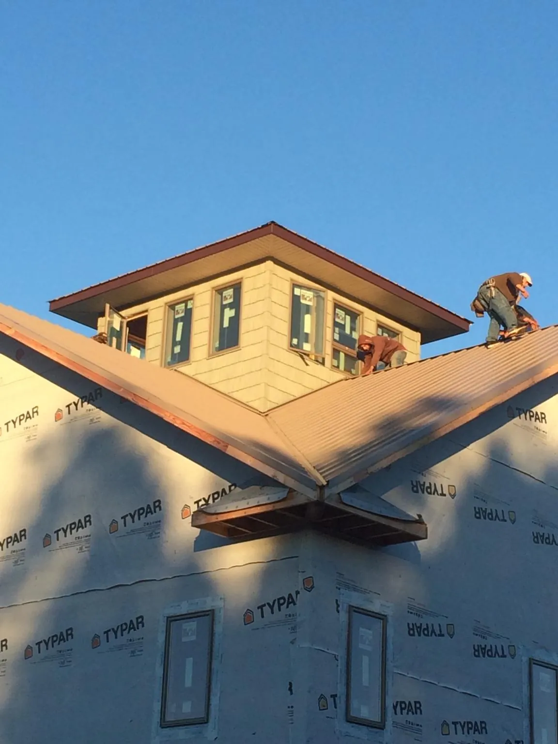 Roofers working around a rooftop cupola on a new metal roof at sunset — Roof Waterproofing in Urbanna by Roofing Brothers